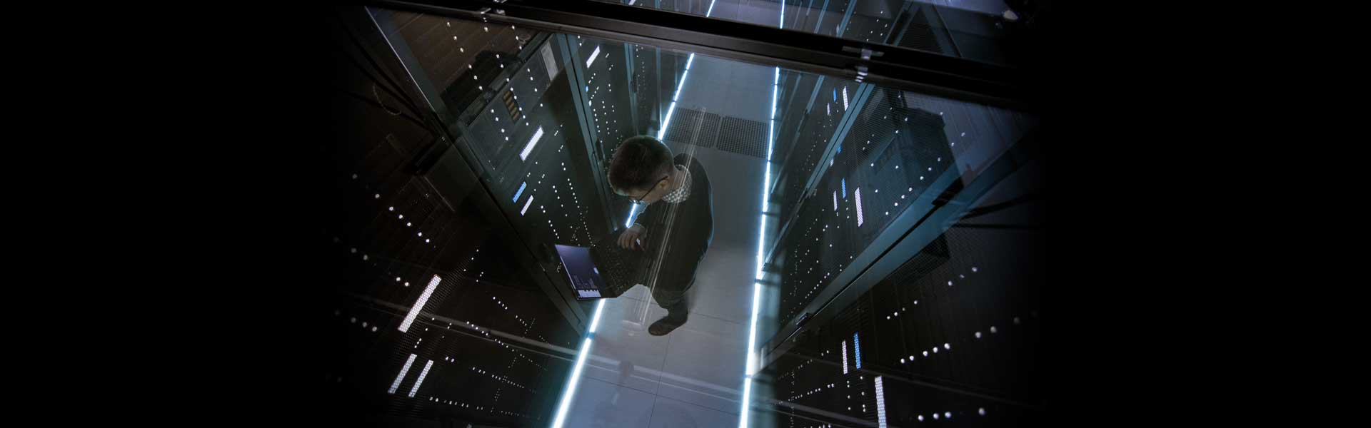 man in server room working on laptop